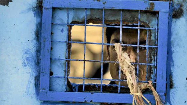 A prisoner looks out of his cell window at the main prison in Kandahar, Afghanistan.