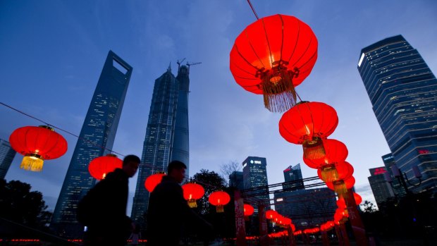 Pedestrians walk under red lanterns in a Shanghai Street.