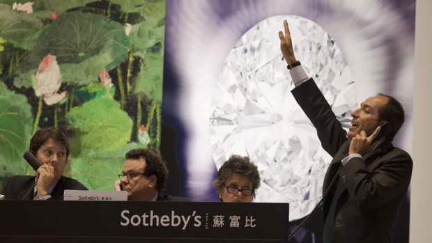 A Sotheby's phone auctioneer gestures during an auction that saw a 118.28-carat white diamond break a world record.