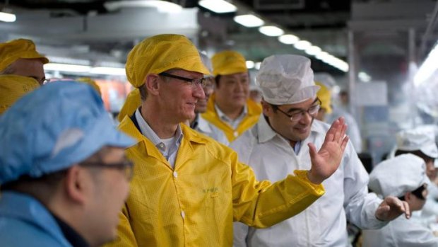 Apple chief executive officer Tim Cook (2nd L) talks to employees as he visits the iPhone production line at the newly built Foxconn Zhengzhou Technology Park, Henan province, in this March 28, 2012 file handout photo.