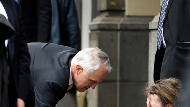 Prime Minister Malcolm Turnbull gives a homeless man five dollars.