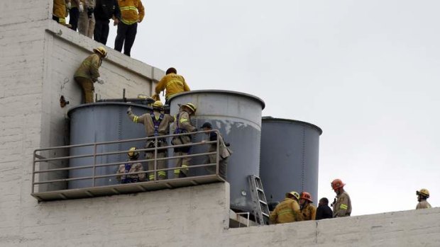Grim find ... firefighters work to remove a body found inside a water tank.