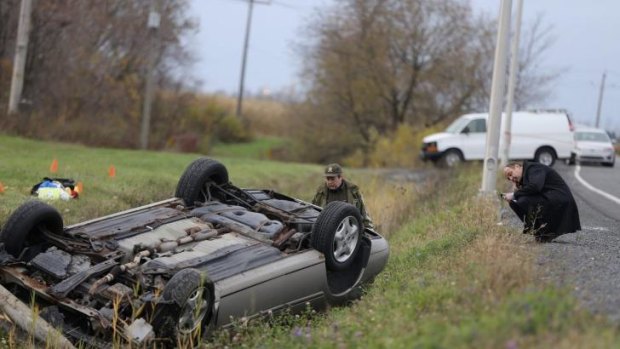 Crash site: Police investigate an overturned vehicle in Saint-Jean-sur-Richelieu, Quebec. The male driver was believed to have hit two soldiers with the vehicle.