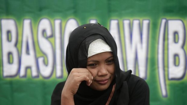 A Filipina Muslim sits in front of a banner during a rally in support of the Bangsamoro Basic Law draft.