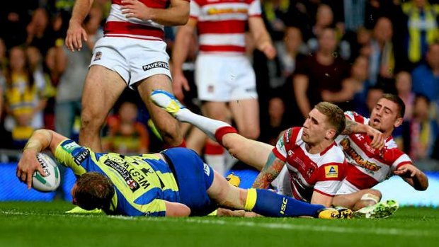 Ben Westwood of Warrington powers through the tackle from Sam Tomkins and Michael McIlorum of Wigan to score.