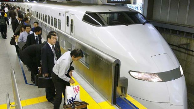 Japanese businessmen line up to take a Shinkansen bullet train at a station in Tokyo.