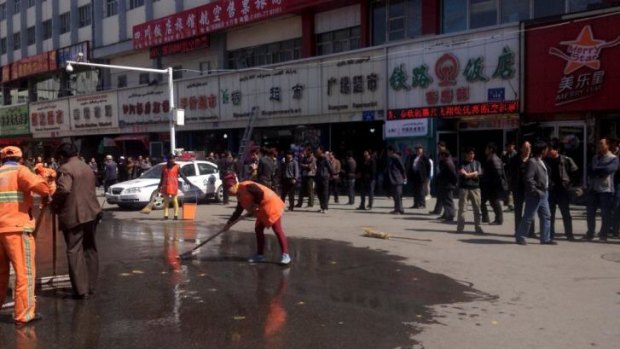 Cleaners scrub the scene of the Urumqi train station blast.