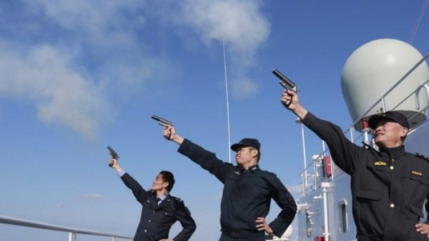 Chinese personnel fire their pistols to signal the start of a naval exercise as they stand on a vessel on the East China Sea.