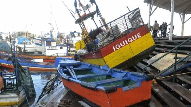 Fishermen inspect boats washed onto a dock after a 2-metre tsunami hit the northern port of Iquique, Chile.