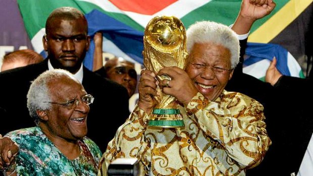 Mandela holds the Jules Rimet World cup beside Archbishop Desmond Tutu in 2004.
