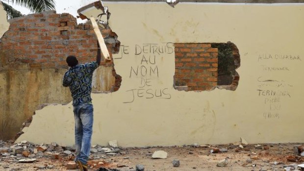 A young man takes part in the destruction of a mosque in the Central African Republic's capital Bangui. The graffiti reads "I destroy in the name of Jesus".