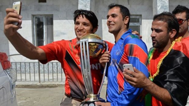 Selfies: Afghan captain Mohammad Nabi holds the 2015 World Cup while teammates take photographs. 