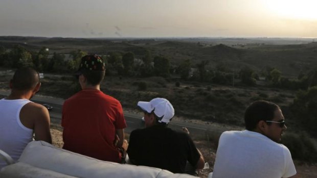 Israelis sit on a sofa on a hill at the Israeli town of Sderot, overlooking the Gaza Strip, as they watch smoke rising following Israeli strikes on Gaza. 