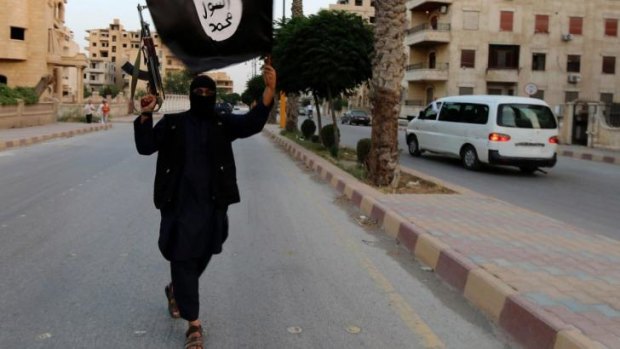 A member loyal to the Islamic State in Iraq waves an ISIL flag in Raqqa.