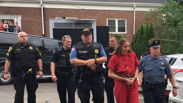 Savilla Stoltzfus, in red, is led to a preliminary hearing outside the Bucks County courthouse.