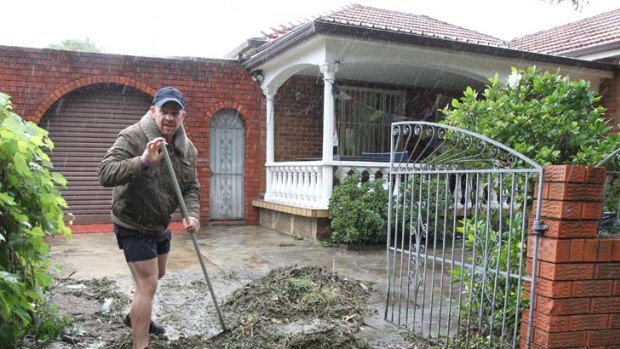 The big clean up ... Resident James Buckle of Marrickville rolls up his sleeves after floodwaters recede.