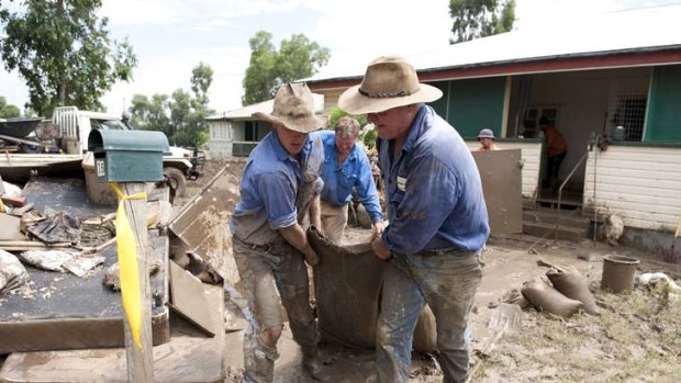 Mucking in &#8230; volunteers empty the flood-ravaged house of Patricia Budd in the Queensland town of Mitchell yesterday. Soldiers are expected to join clean-up efforts today.