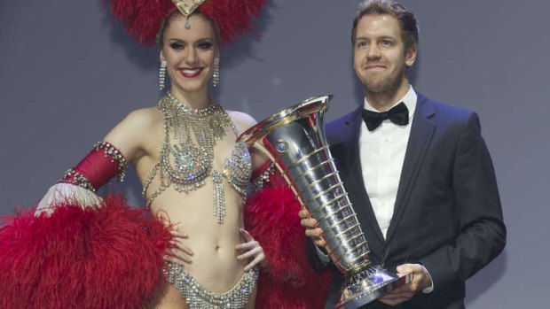 Sebastian Vettel holds his trophy next to a Moulin Rouge dancer during the 2013 FIA Prize-Giving gala in Saint-Denis.