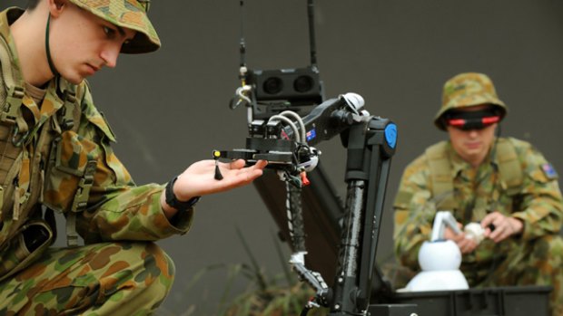 Soldier David Nihill inspects the work of the OzBot, which delivers sensory information on an object from a distance.