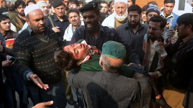 Hospital security guards carry a student injured in the shootout at a school under attack by Taliban in Pakistan.
