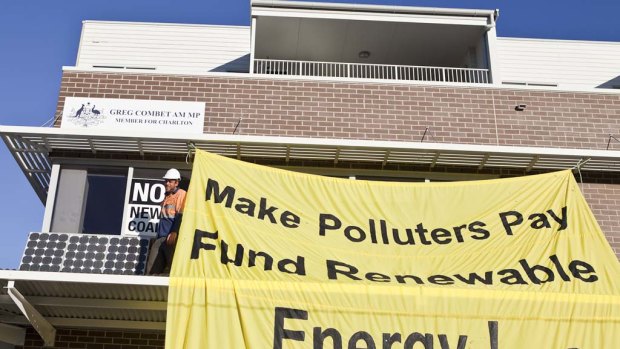 Climate change activists hang banners from, and place solar panels on, federal Climate Change Minister Greg Combet's office.