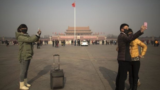 Tourists in masks use mobile phone cameras to snap shots of themselves during a heavily polluted day on Tiananmen Square in Beijing.