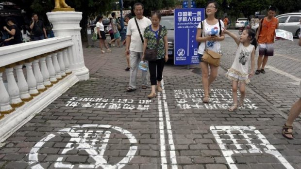Residents walk on a lane painted with instructions to separate those using their phones as they walk from others in southwest China's Chongqing Municipality.