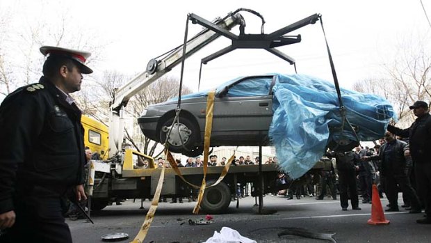 People gather around as Mostafa Ahmadi Roshan's car is removed.