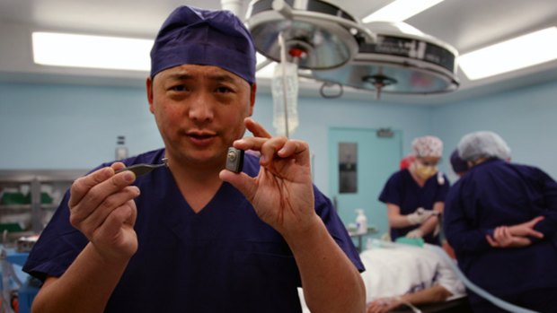 Surgeon Phillip Chang looks at the hearing implant that he will place in his patient Colin Hughes during surgery at The Hills Private Hospital.