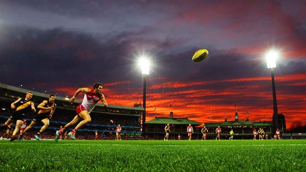 Red flash: As the setting sun leaves its dazzling mark, Sydney's Josh Kennedy leads the race for the ball at the SCG on Sunday.