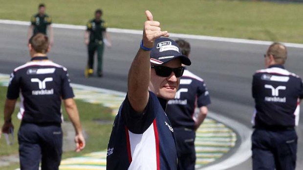 Rubens Barrichello waves to photographers as he undertakes an inspection of the Interlagos racetrack with team members.