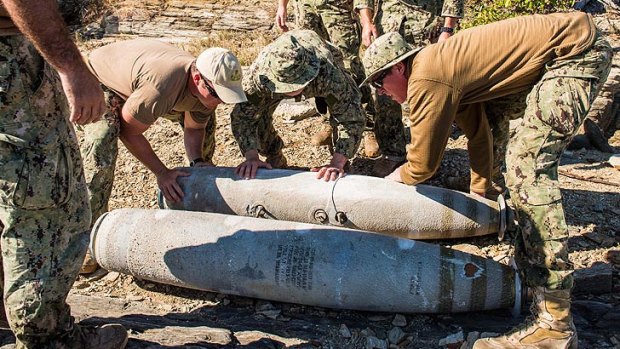 Members of the US Navy place bombs recovered from the Great Barrier Reef at a disposal site near Shoalwater Bay Training Area.