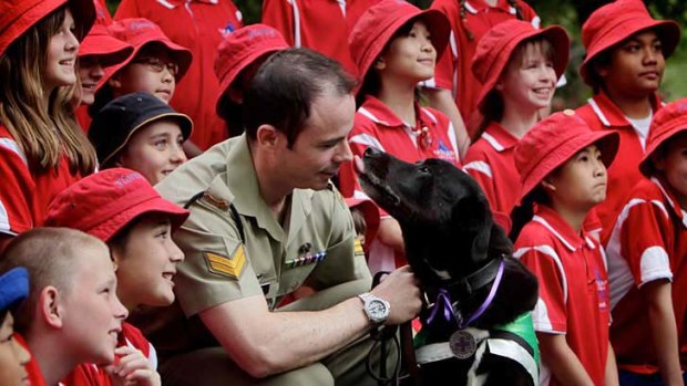 Sarbi with her Purple Cross award, dog trainer Corporal Adam Exelby and students from Florey Primary School at the Australian War Memorial.