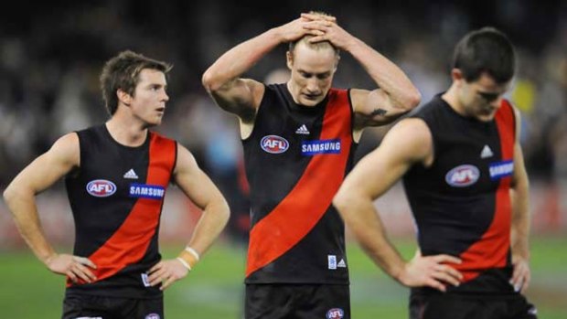 After yet another dreadful loss, Essendon's Jason Winderlich, centre, holds his head  in frustration, echoing the sentiments of players and fans alike.