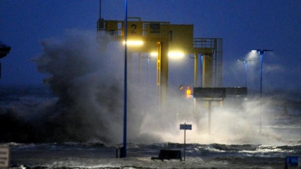 Waves lash against the ferry pier on the North Sea coast in Germany.