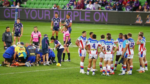 Knights players huddle as their teammate Alex McKinnon is prepared to be carried from the pitch.