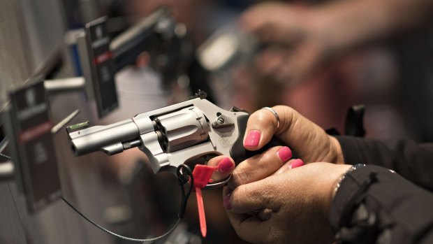 An attendee handles a gun at the National Rifle Association annual show in Nashville.