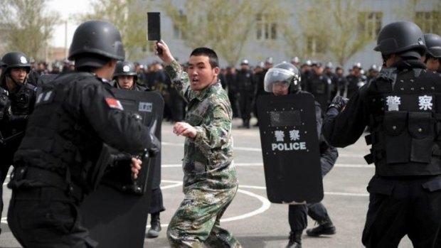 A participant playing the role of an attacker faces riot police during a security drill in Urumqi, Xinjiang.