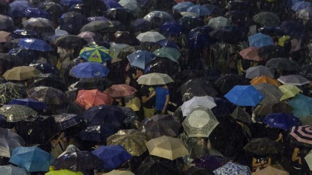 Pro-democracy protestors use umbrellas to shield themselves from heavy rain in Hong Kong.