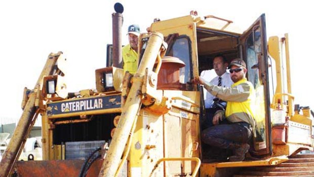 Tony Abbott sits behind the wheel of a bulldozer during a visit to McCoskers Contracting in Gladstone, Queensland.