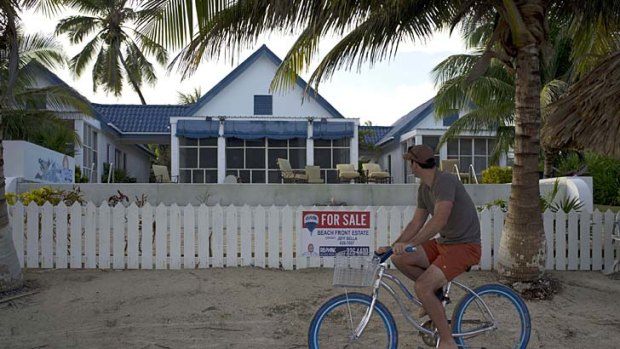 A man rides a bicycle past the beachside entrance to the home of software company founder John McAfee in Ambergris Caye, Belize.