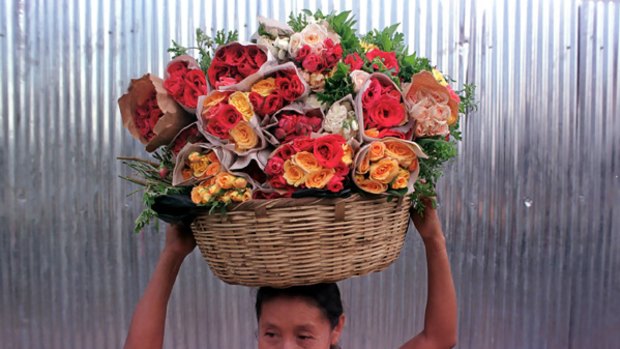 In bloom ... a woman carries a basket of flowers for sale in San Salvador, the capital of El Salvador.