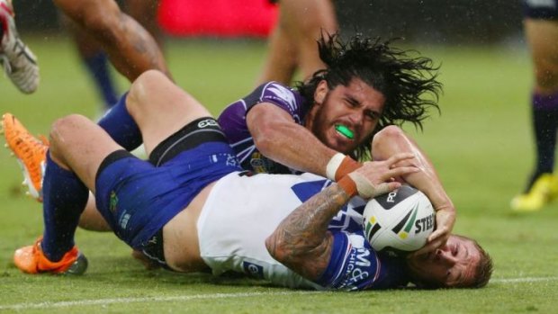 Power struggle: Trent Hodkinson of the Bulldogs scores a try as Tohu Harris of the Storm tackles him.