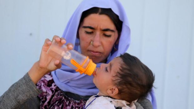 A displaced Iraqi woman from the Yazidi community feeds her child after crossing the Iraqi-Syrian border.