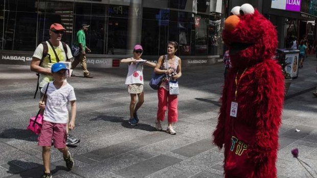 A person dressed in an Elmo costume stands in the Times Square region of New York.
