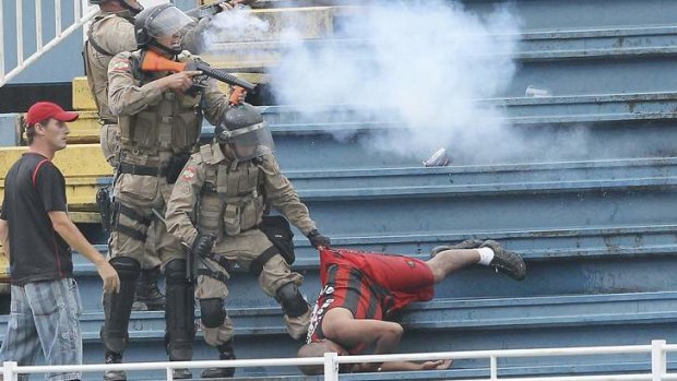 Policemen fire rubber bullets during clashes between Vasco da Gama soccer fans and Atletico Paranaense fans at their Brazilian championship match in Joinville on December 8, 2013.