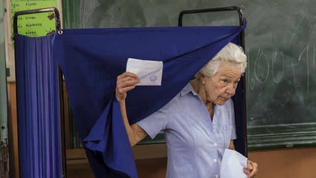 A woman leaves a polling booth to cast her ballot during the referendum in Athens, Greece.