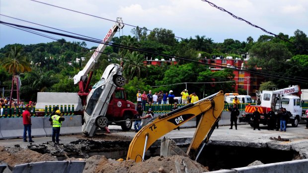 Rescue workers use a crane to lift a vehicle that drove into a sinkhole killing the driver and his son in Mexico on Wednesday.