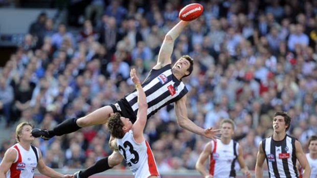Collingwood's Darren jolly rises above  St Kilda's Justin Koschitzke to tap a centre  bounce towards his teammates during yesterday's grand final draw at the MCG.
