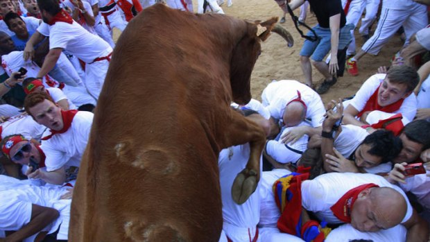 A fighting bull leaps over revellers upon entering the bullring following the first running of the bulls of the San Fermin festival in Pamplona.